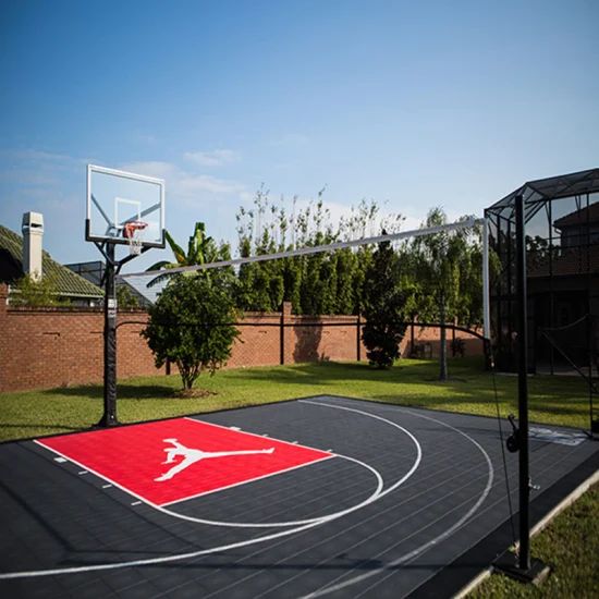 El baloncesto usado que suela el patio trasero residencial cancha la superficie flexible de los deportes